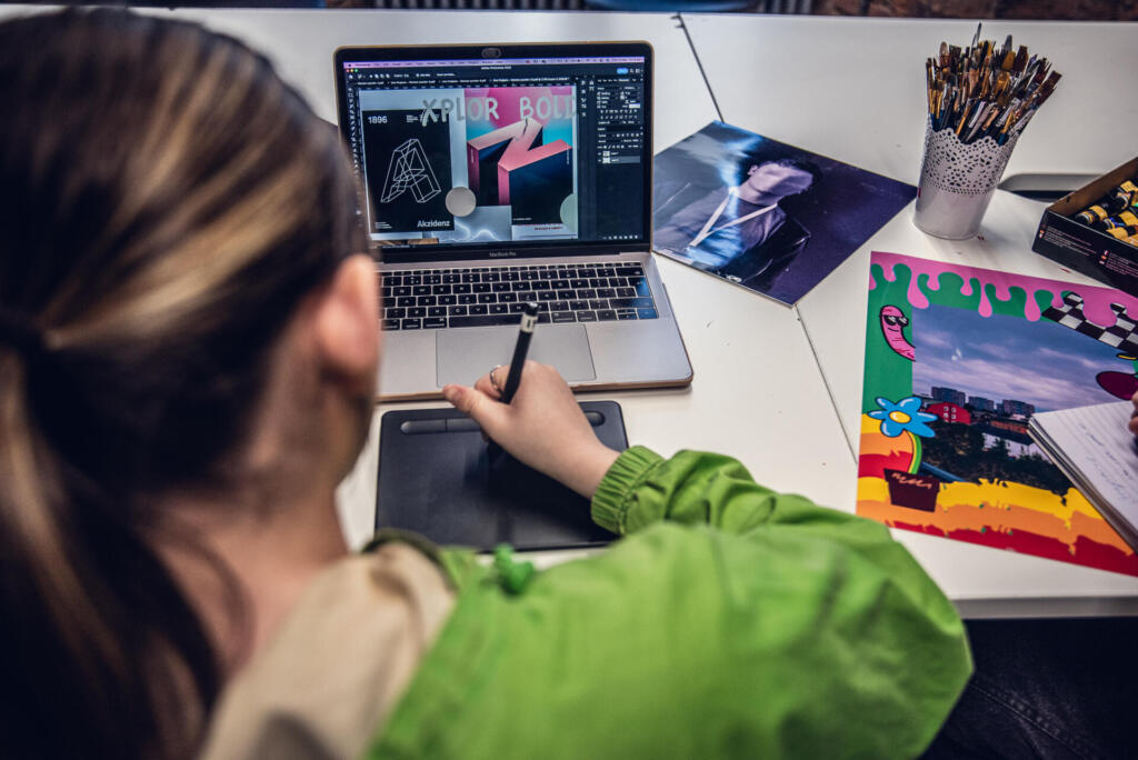 Designer working on a laptop with color swatches and art supplies