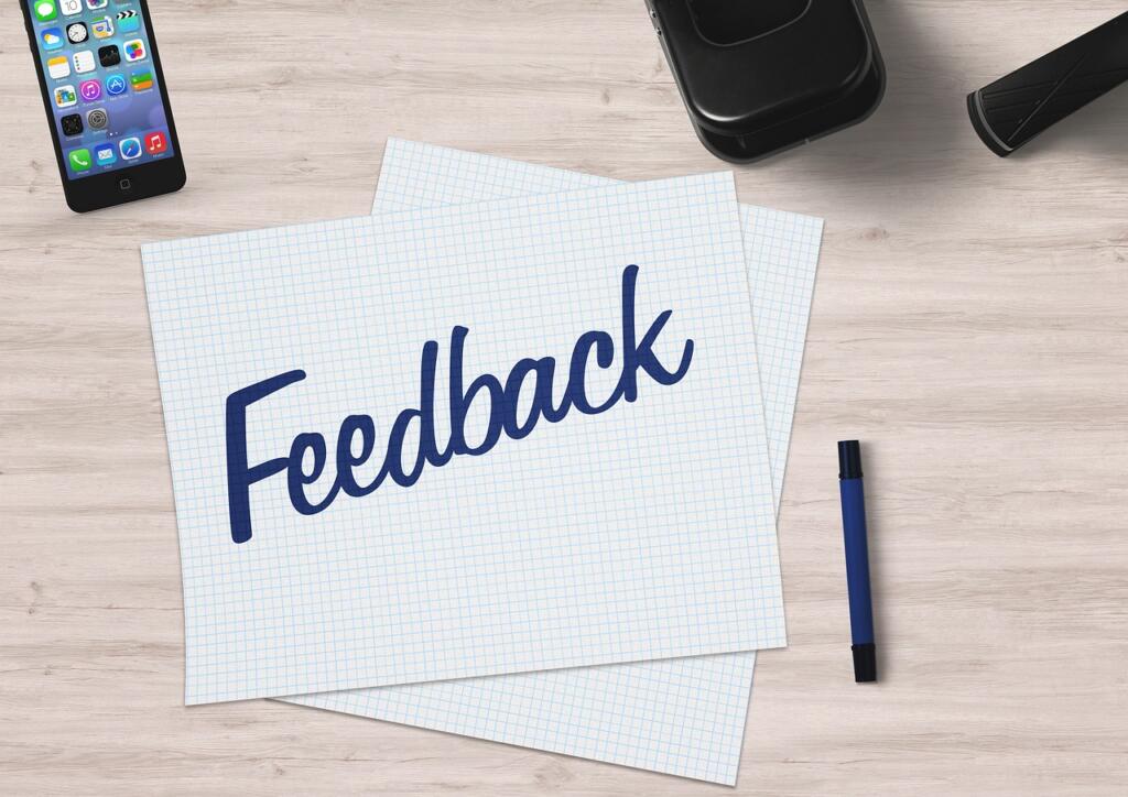 Feedback written on a note card on a desk next to a phone and pen