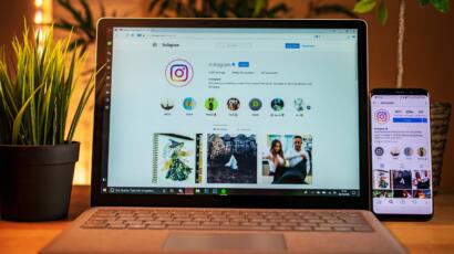 Laptop on a desk showing an Instagram photo grid