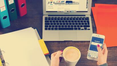 Desk with a laptop, notebook, phone and cup of coffee