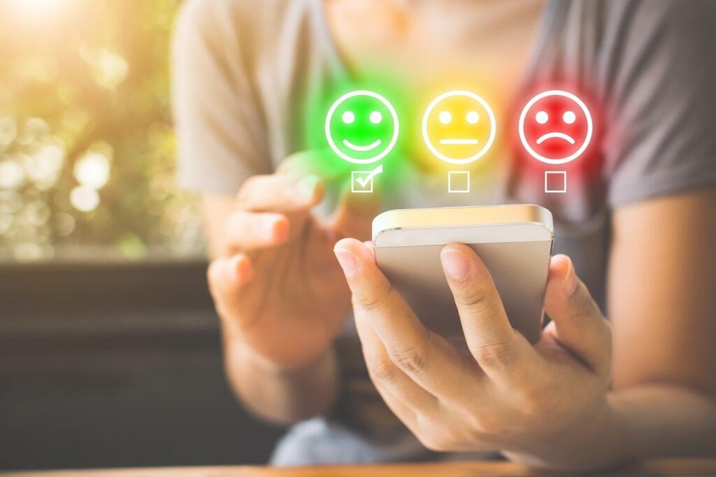 Person choosing a happy face rating on a phone screen