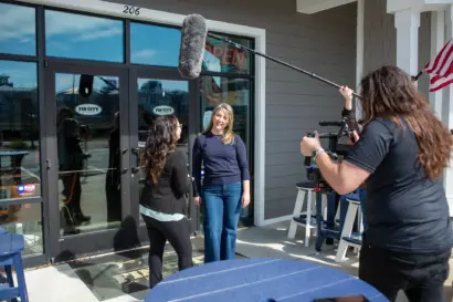 Shorecraft crew filming with a boom microphone outside a storefront