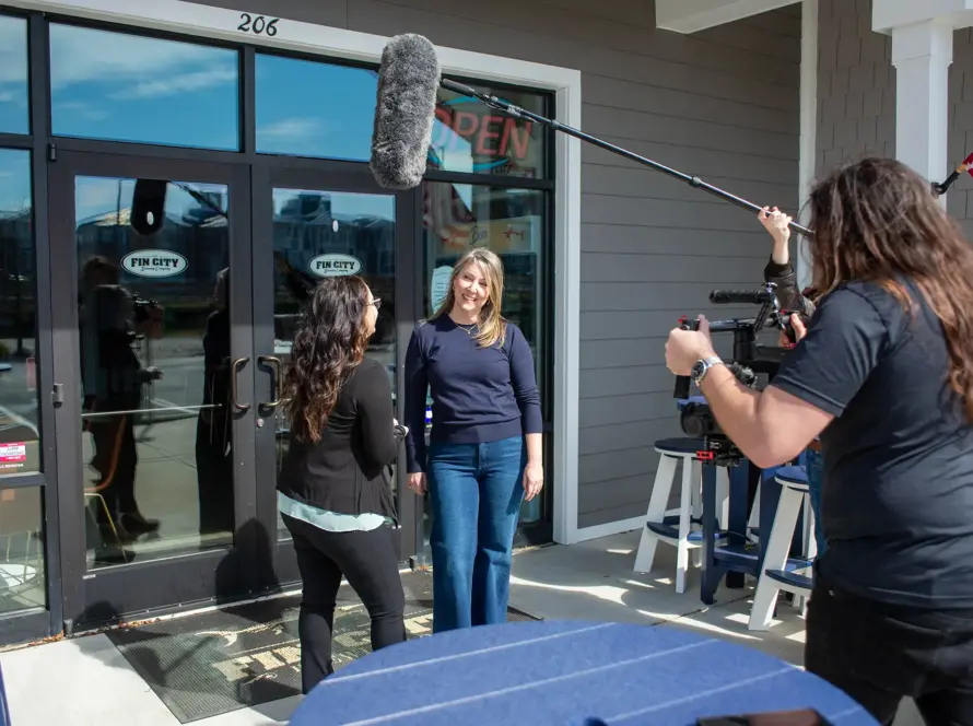 Shorecraft crew filming with a boom microphone outside a storefront